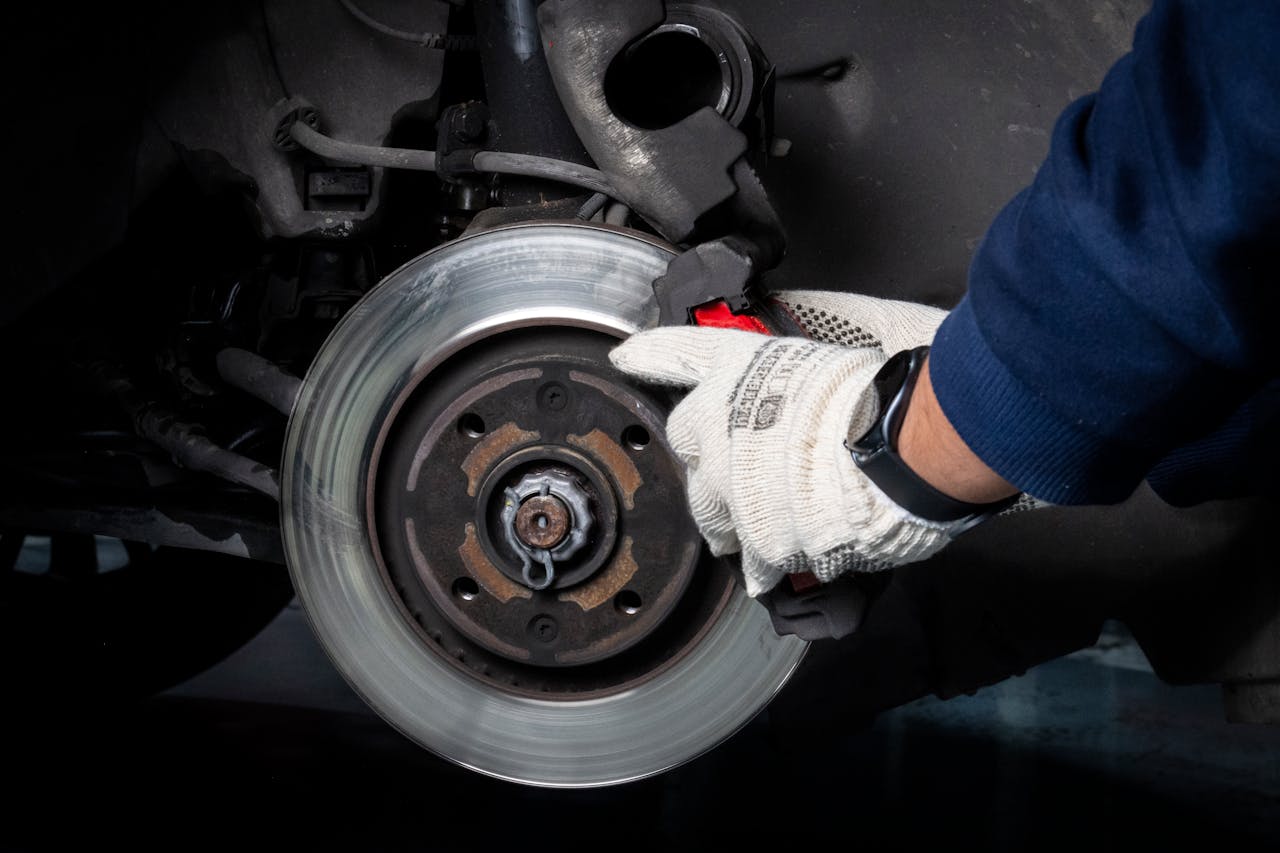 about-us Mechanic working on car brake system in a workshop setting.